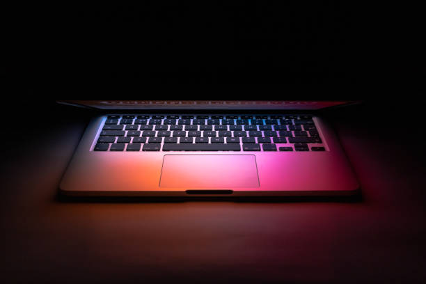 istock a laptop half closed in the dark with colourful glow 1321551360