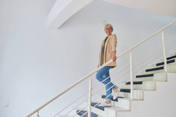 istock Cheerful midle aged woman wearing elegant jacket stands on empty staircase 1321556287