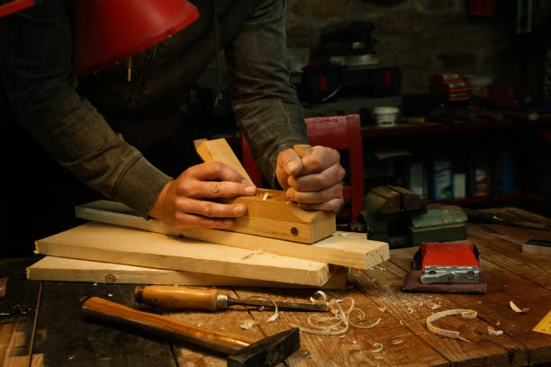 istock Carpenter planing wood in workshop with a hand planer 1321557012
