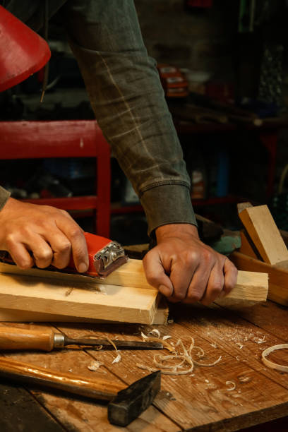 istock Carpenter is using sandpaper on a piece of wood in workshop. Sanding wooden plank. 1321557027
