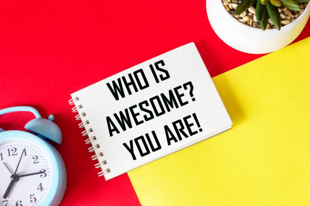 istock Who is cool You Positive affirmation and personal development concept. Written on a notepad and a red and yellow background. Near an alarm clock and a cactus 1321558122