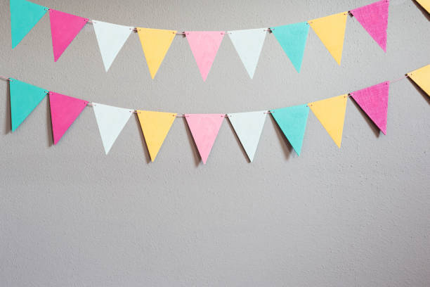 Colorful party flags over cement concrete gray wall texture background, pastel birthday colored flags with copy space Holiday concept beauty