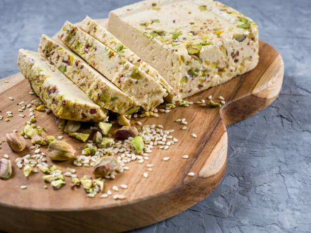 istock Sesame halva with pistachios on a teak chopping board on a grey background. 1321581099