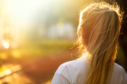 young woman getting sunlight on her hair, back view