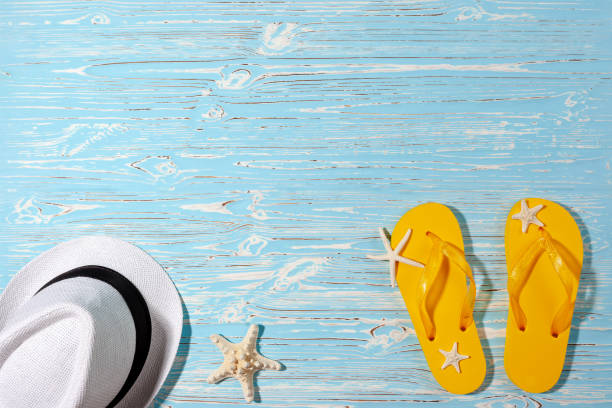 istock yellow rubber flip flops, white beach hat, starfish on a blue wooden background 1321582699