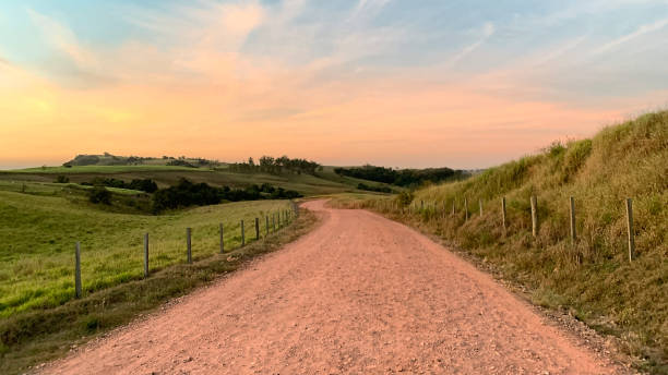 Gravel road in the countryside Gravel road at dawn, through green pastures towards mountains, in the countryside rural scene stock pictures, royalty-free photos & images