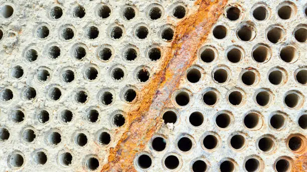 Photo of Selective focus tube sheet or boiler or plate of heat exchanger closeup texture macro background full of hard insoluble mineral deposits salts scale and corrosion. Trypophobia concept. 16x9