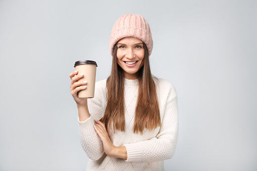 Portrait of beautiful young woman with coffee on grey background