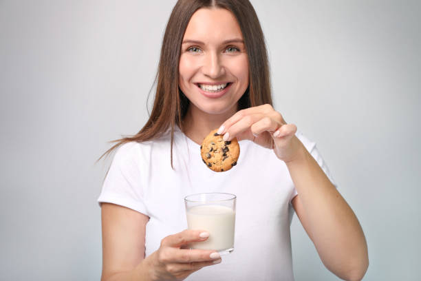 istock Beautiful young woman with milk on grey background 1321598140
