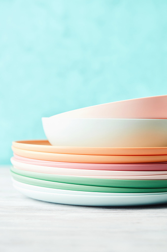 Collection of reusable colorful plastic dishes and bowls against bright blue background
