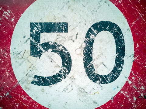 A very weathered 50 speed sign close-up