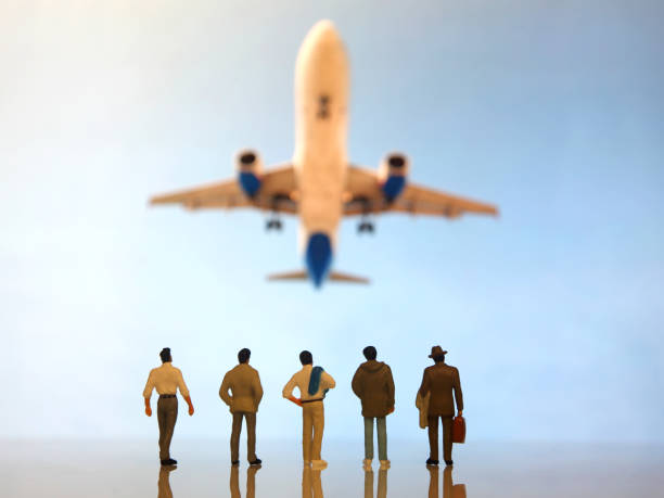 istock miniature people. a group of different people watching a flying passenger plane 1321601915