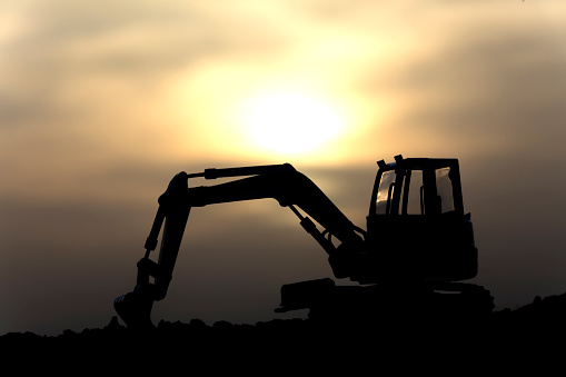 silhouette of heavy excavator over dugout