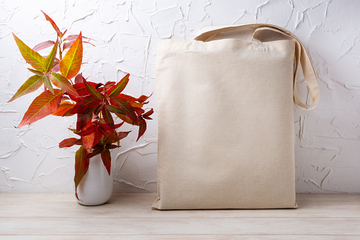 Canvas tote bag mockup with red fall grass in the white vase. Rustic linen shopper bag mock up for branding presentation