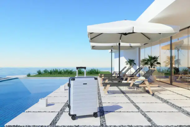 Photo of Luxury Holiday Villa Exterior With Lounge Chairs And Suitcase Near The Swimming Pool. Holiday Concept.