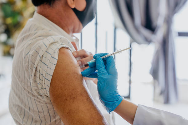Senior man getting a vaccine injection on his arm Close up image of an Asian senior man getting a vaccine injection on his arm from a doctor herd immunity photos stock pictures, royalty-free photos & images