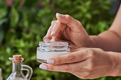 Close up of woman hands holding jar of moisturizing cream.