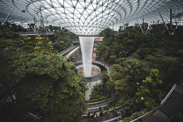 Singapore, September 6, 2020: People watching a spectacular spaceship waterfall inside the Changi Airport in Singapore. The futuristic waterfall is located inside the Jewels shopping mall in Terminal 1 and Terminal 2.