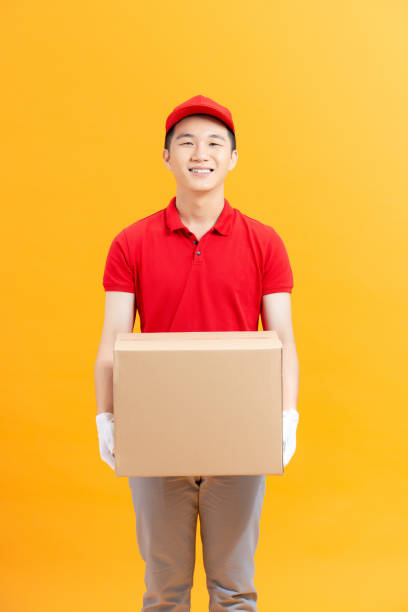 istock happy delivery man with box Isolated on a yellow Background. 1321625100