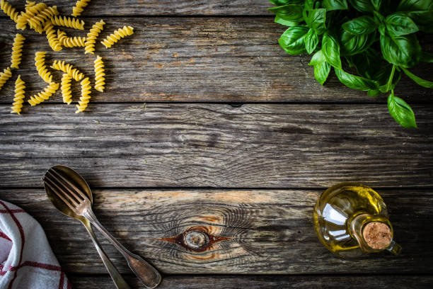 Uncooked fusilli, oil olive, fresh basil on wooden table