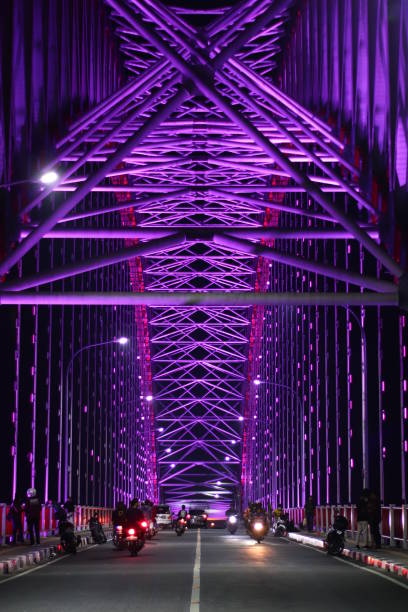 a bridge that many vehicles pass by surrounded by lights along the road