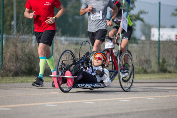 Disabled Athlete who Trains with her Hand Bike with Cyclist and Runners at her Side Parma, Italy - October 2020: Disabled Athlete who Trains with her Hand Bike with Cyclist and Runners at her Side. paralympic games stock pictures, royalty-free photos & images