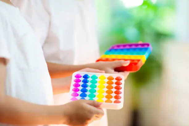 Photo of Kids with pop it sensory toy. Stress relief.