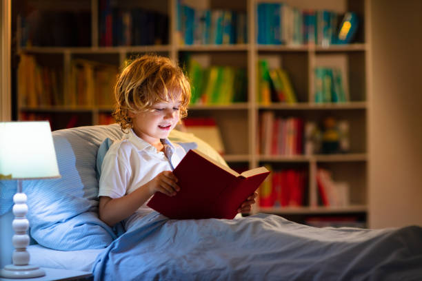 istock Child reading book in bed. Kids read at night. 1321649849