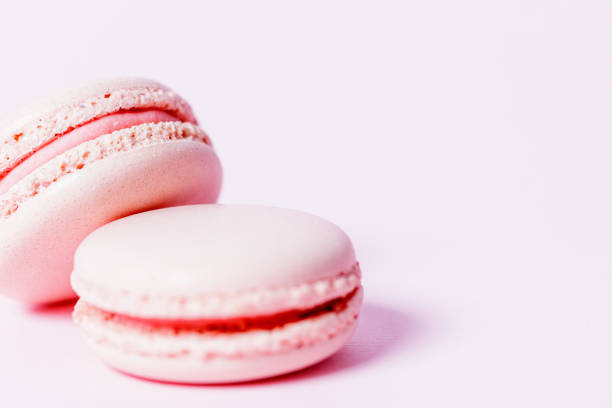 istock Nude colored macaroons with rose filling on pale pink background 1321650159