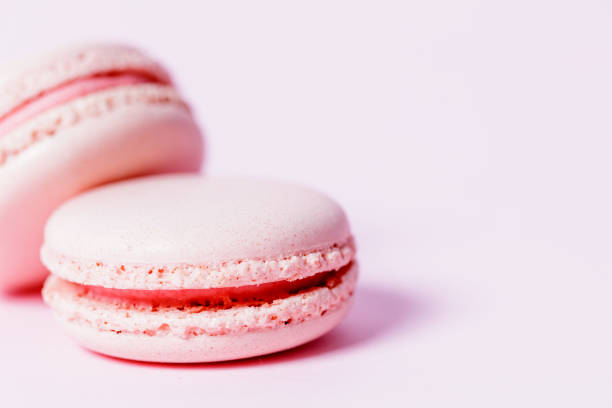 istock Nude colored macaroons with rose filling on pale pink background 1321650622