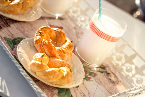 bretzels de massepain avec un verre de lait de coco pour le petit déjeuner. concept de routine matinale. ombres dures. mise au point sélective. - twisted cheese biscuit pastry photos et images de collection