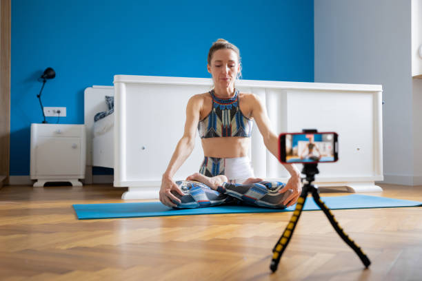 istock Yoga instructor making vlog at home, sitting in lotus pose with hands on knees 1321650939