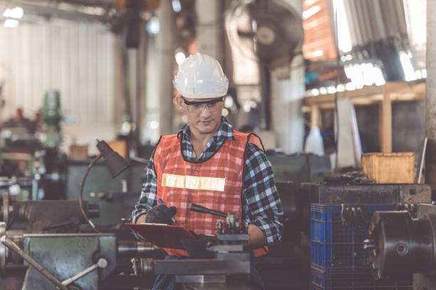 istock engineers in overalls and hardhats holding folder with documents and looking away in the factory 1321651090