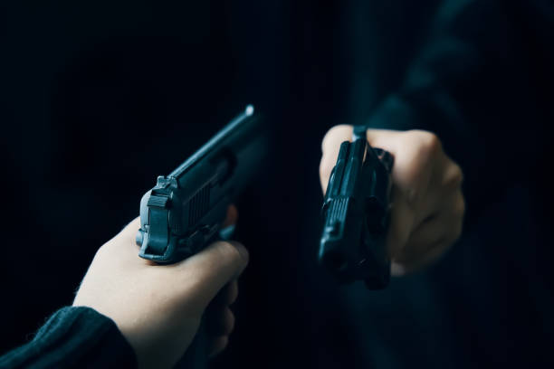 istock Two men's hands with weapons pointed at each other. 1321651248