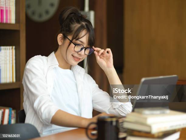 Side View Of Female Student Doing Homework On Digital Tablet In Cafe Stock Photo - Download Image Now