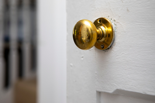 Brown wooden entrance door with gold-plated forged handles and ornate, outside.