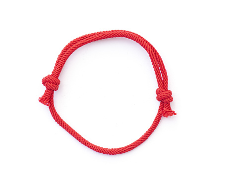 Red thread, string as amilet for wrist isolated on white. Red braslet with knots. Top view.