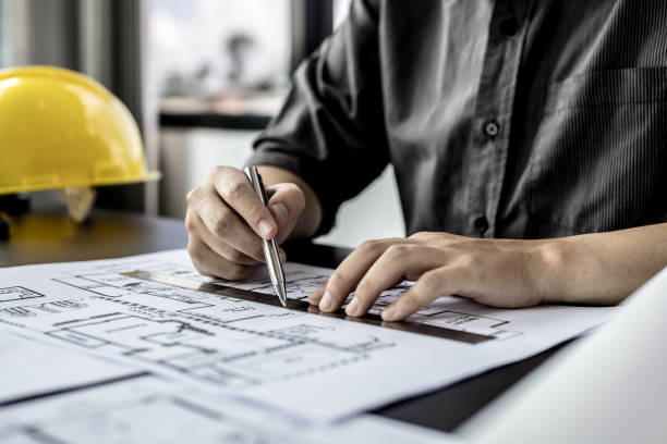 istock A close-up, an architect, a house designer holding a pen, pointing to a house plan to examine the design plan before discussing the details with the client. Interior design and decoration ideas. 1321659621