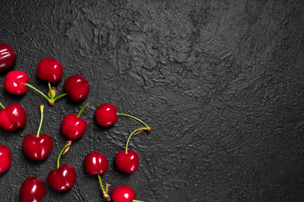 istock Ripe and delicious cherry on black background 1321660041