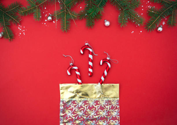 istock Red flat lay minimalistic Christmas background with fir branches. Gift bag with candy. Top view, copy space, place for text 1321661221