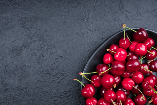 istock Ripe and delicious cherry on black background 1321662471