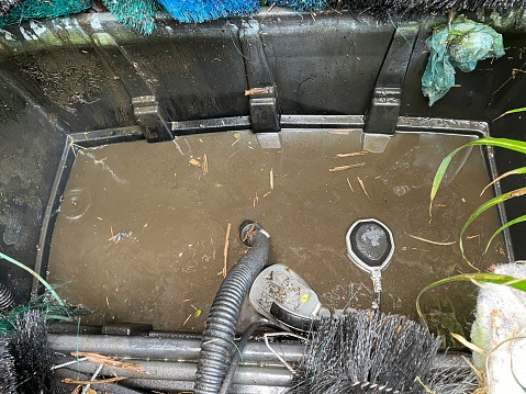 Photo showing large garden pond filter with water pumped out and brushes removed for cleaning. This filter is necessary to maintain the water quality of a koi carp pond in order for the fish to thrive and grow, enjoying clear, purified pond water.