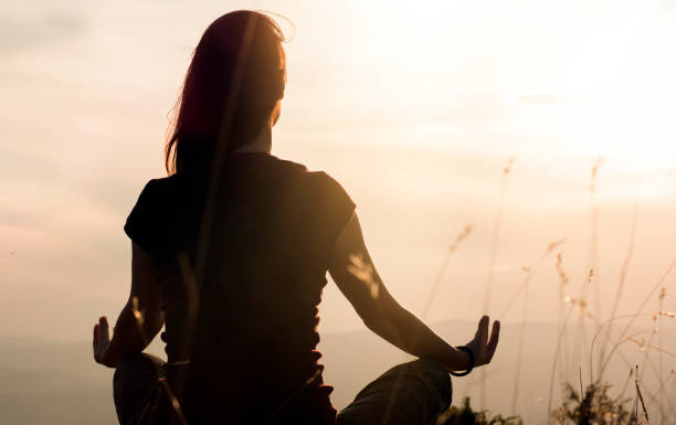 silhouette d’une jeune femme pratiquant le yoga à l’extérieur - aura photos et images de collection