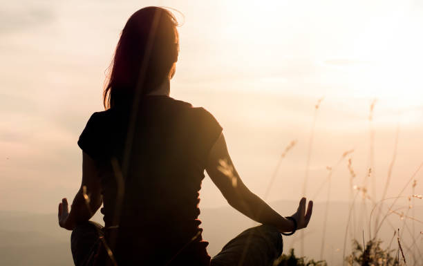 silhouette di giovane donna che pratica yoga all'aperto - aura foto e immagini stock