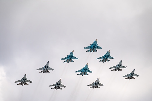 Moscow, Russia - May 5, 2021: Fighters Su-35S and Su-30SM with Su-34 bombers in the blue sky over Red Square in the tactical wing group. The aviation part of the Victory Day parade in Moscow. Group of supersonic aircraft Su-34 Bombers Fullback, Su-35S Flanker-E and Su-30SM Flanker-C