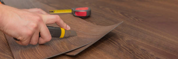 istock Vinyl flooring installation. Easy installation and cutting with a knife, Master cuts vinyl plank before installation, brown heated floor. Copy space 1321667446