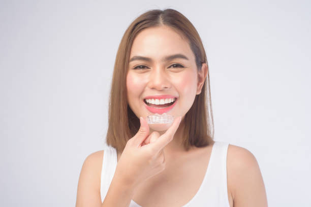 Young smiling woman holding invisalign braces over white background studio, dental healthcare and Orthodontic concept. A young smiling woman holding invisalign braces over white background studio, dental healthcare and Orthodontic concept. orthodontist stock pictures, royalty-free photos & images