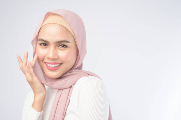 Portrait of young smiling muslim woman wearing a pink hijab over white background studio. stock photo