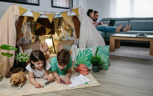 istock Children playing camping at home while their parents work with laptop 1321677213
