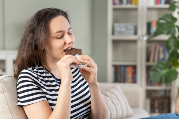 istock Young woman eating chocolate bar 1321677363